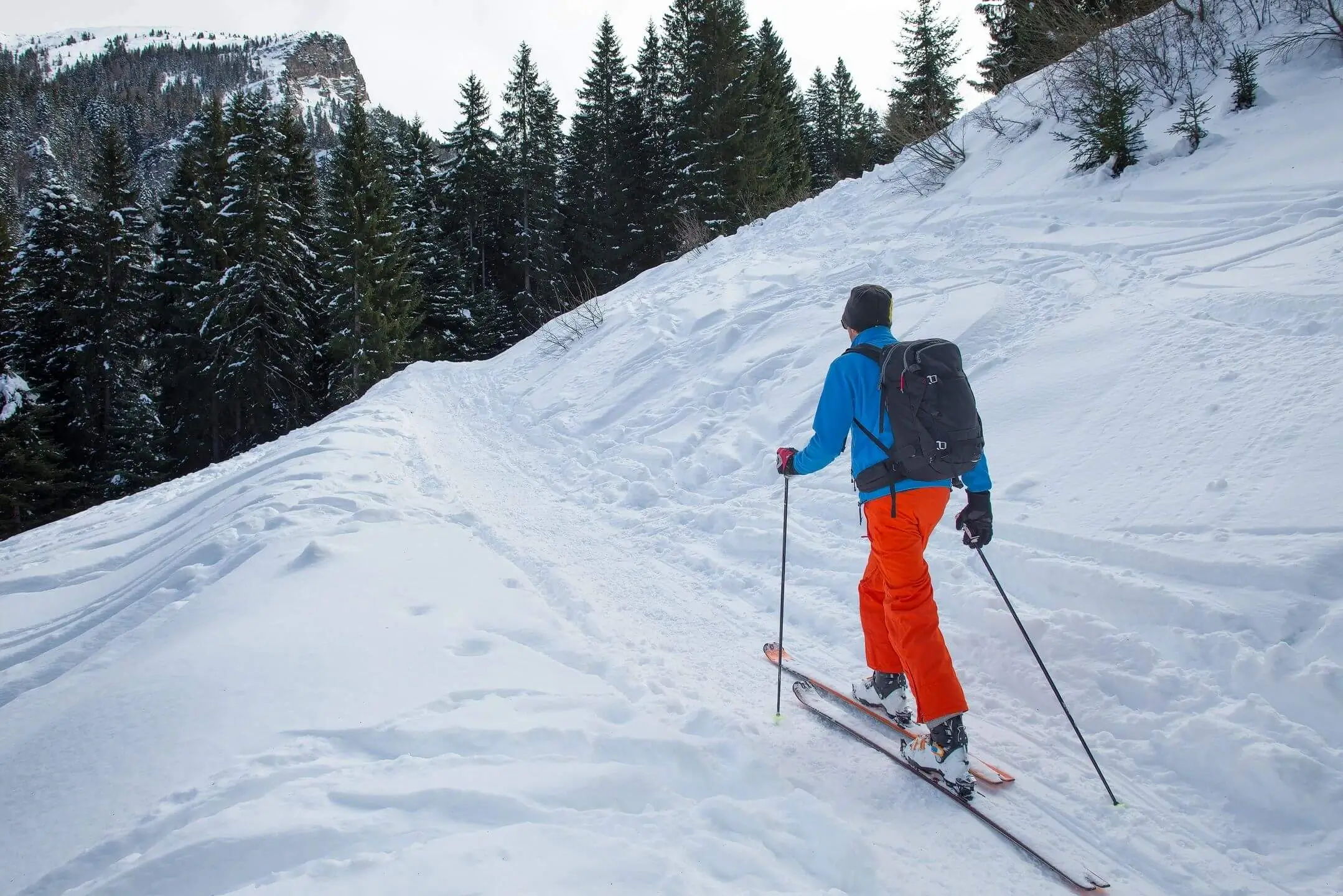 Backcountry skier climbing snowy slope with poles