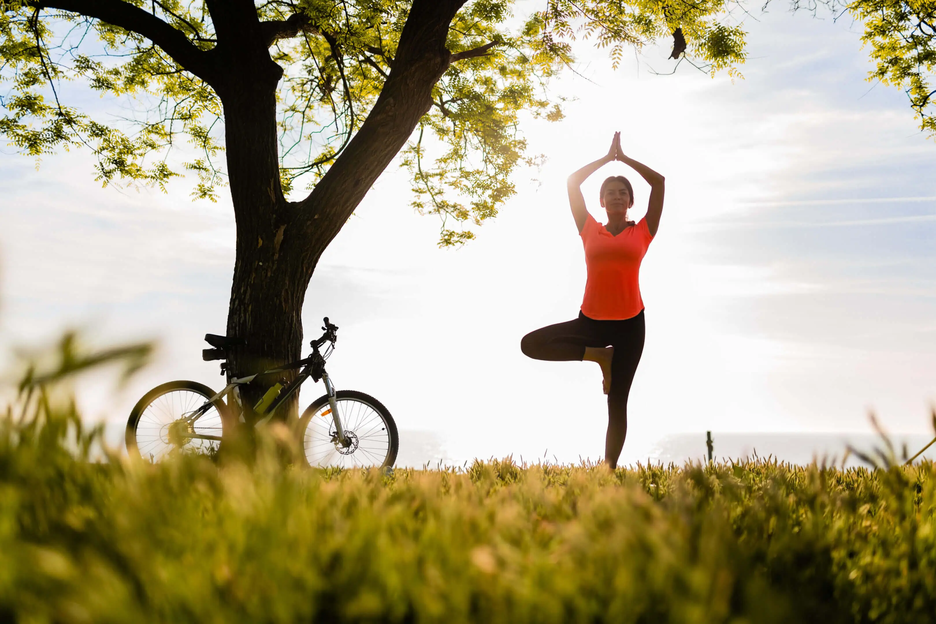 Person doing tree pose near bicycle