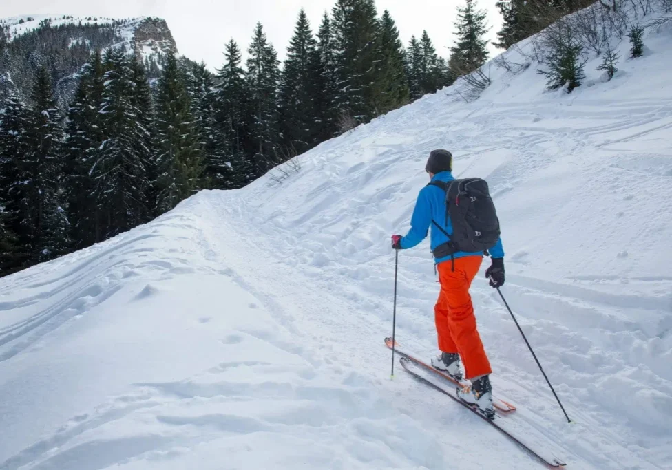 Backcountry skier climbing snowy slope with poles